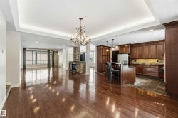 Open concept living space featuring hardwood floors, a stone-clad fireplace, and a kitchen with wood cabinetry and stainless steel appliances - 
