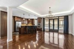 The property features rich hardwood flooring, a kitchen with dark wood cabinetry and stainless steel appliances, and a spacious dining area with a decorative chandelier - 