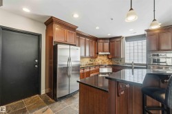 Kitchen featuring rich wood cabinetry, stainless steel appliances, dark countertops, and a tiled backsplash - 