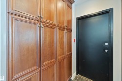 Entryway featuring a dark door, dark floor tiles, and extensive built-in cabinetry with decorative handles - 
