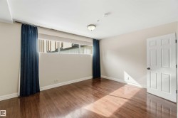 Primary Bedroom featuring dark hardwood floors, light-colored walls, and a window with dark blue curtains and a roller blind - 