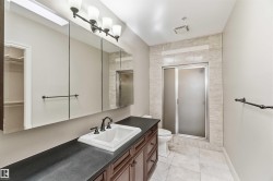The bathroom features a vanity with a white rectangular sink, dark cabinetry, and a dark countertop - 