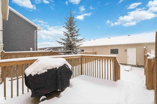 The property features a spacious wooden deck, a mature evergreen tree, and a wooden fence - 1313 Chappelle Boulevard, Edmonton, AB - Outdoor With Deck Patio Veranda
