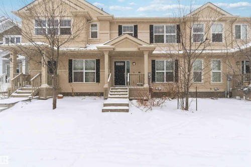 The property features a multi-story exterior with light-colored siding, dark window shutters, and a covered front entry with columns - 1313 Chappelle Boulevard, Edmonton, AB - Outdoor With Facade