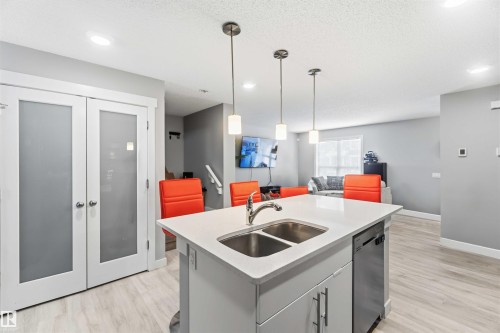 The kitchen features a functional island with a double sink, stainless steel faucet, and a dishwasher - 1313 Chappelle Boulevard, Edmonton, AB - Indoor Photo Showing Kitchen With Double Sink
