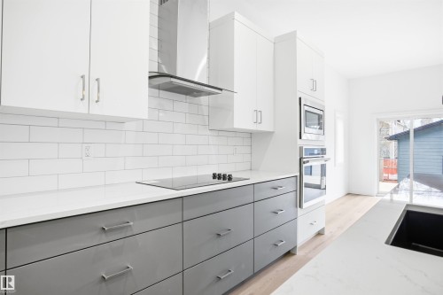 The kitchen features white upper cabinetry, gray lower cabinetry, a white subway tile backsplash, and stainless steel appliances - 9807 90 Avenue, Edmonton, AB - Indoor Photo Showing Kitchen With Upgraded Kitchen