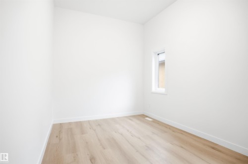 This room features light-toned wood-style flooring and bright white walls with matching baseboards - 9807 90 Avenue, Edmonton, AB - Indoor Photo Showing Other Room