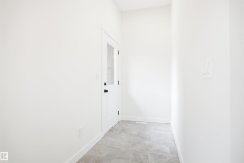 Entryway with white walls, a white door with a window pane, and grey tiled flooring - 9807 90 Avenue, Edmonton, AB - Indoor Photo Showing Other Room