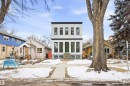 The property features a modern facade with white siding and black trim, complemented by a vibrant green front door - 9807 90 Avenue, Edmonton, AB  - Outdoor With Facade 