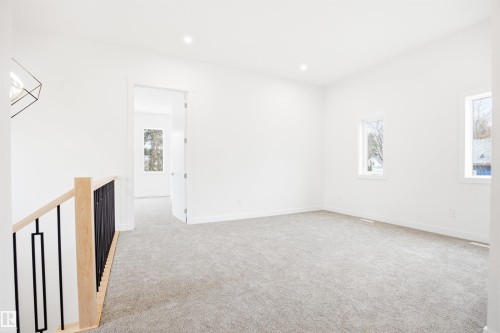 This expansive room features light gray carpeting, crisp white walls, and two windows providing natural light - 9807 90 Avenue, Edmonton, AB - Indoor Photo Showing Other Room