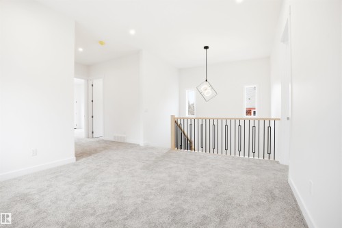 Spacious landing area featuring light grey carpeting, recessed lighting, and a contemporary light fixture - 9807 90 Avenue, Edmonton, AB - Indoor Photo Showing Other Room