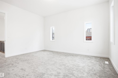 This expansive room features light-colored carpeting and white walls, creating a bright and airy atmosphere - 9807 90 Avenue, Edmonton, AB - Indoor Photo Showing Other Room