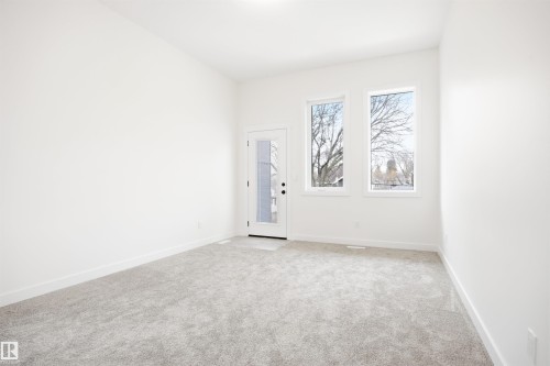 This bright room features a neutral color palette, plush grey carpeting, and a glass-paneled door that provides access to the outdoors - 9807 90 Avenue, Edmonton, AB - Indoor Photo Showing Other Room