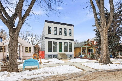 The property features a modern white facade with contrasting black trim and numerous windows, set back from a sidewalk and street - 9807 90 Avenue, Edmonton, AB - Outdoor With Facade