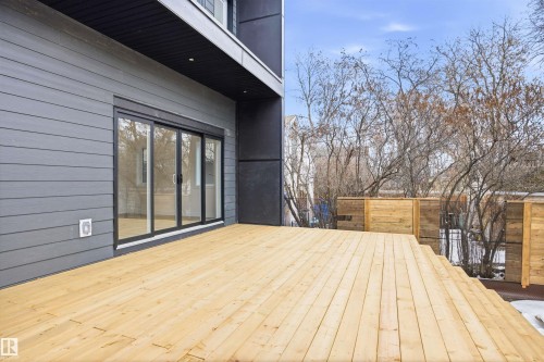The property features a spacious outdoor deck with light-toned wooden planks, offering ample space for entertaining - 9807 90 Avenue, Edmonton, AB - Outdoor With Deck Patio Veranda With Exterior
