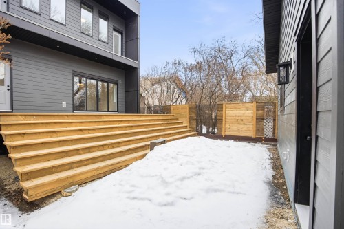 The property features a spacious wooden deck with wide steps, a backyard area, and a light wood fence - 9807 90 Avenue, Edmonton, AB - Outdoor With Exterior