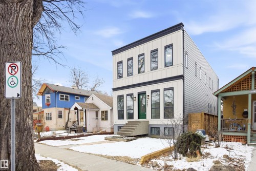 The property features a multi-story exterior with light-colored vertical siding and dark trim, highlighted by a vibrant green front door - 9807 90 Avenue, Edmonton, AB - Outdoor