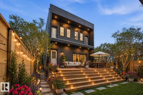 Contemporary rear exterior with a multi-level wooden deck featuring integrated step lighting. Virtually staged - 9807 90 Avenue, Edmonton, AB - Outdoor With Deck Patio Veranda