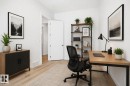 Well-lit room with wood-finish flooring, featuring a modern wood and metal shelving unit and a complementary wood and metal desk. Virtually staged - 9807 90 Avenue, Edmonton, AB  - Indoor Photo Showing Office 