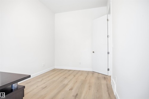 Bright room featuring light-toned flooring, white walls, and a door with a chrome handle - 9807 90 Avenue, Edmonton, AB - Indoor Photo Showing Other Room