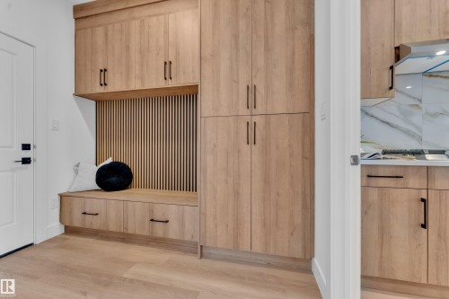 Entryway featuring light wood cabinetry with dark hardware, a built-in bench, and light wood flooring - 110 Eldridge Point(E), St. Albert, AB - Indoor