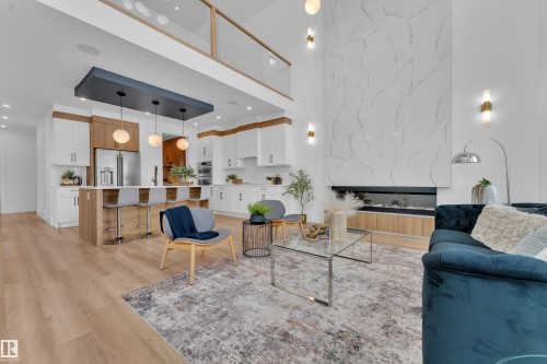 The property features an open-concept living area with high ceilings, a grand fireplace with a natural stone surround, and light wood flooring - 110 Eldridge Point(E), St. Albert, AB - Indoor Photo Showing Living Room With Fireplace