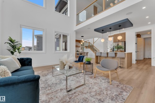 The property features an open concept living area with high ceilings, large windows, and light wood flooring - 110 Eldridge Point(E), St. Albert, AB - Indoor Photo Showing Living Room