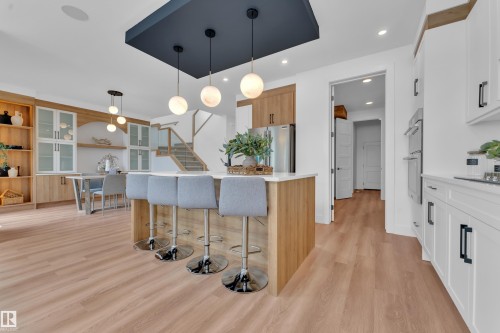 The open-concept kitchen features a large island with seating, pendant lighting, and light wood flooring - 110 Eldridge Point(E), St. Albert, AB - Indoor Photo Showing Kitchen With Upgraded Kitchen
