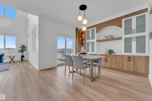 The property features light-toned flooring, a dining area with a modern chandelier, and built-in cabinetry with both solid and glass-front doors - 110 Eldridge Point(E), St. Albert, AB - Indoor Photo Showing Dining Room