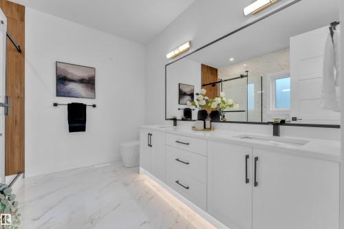 The bathroom features a double vanity with white cabinetry, matte black hardware, and a large mirror - 110 Eldridge Point(E), St. Albert, AB - Indoor Photo Showing Bathroom