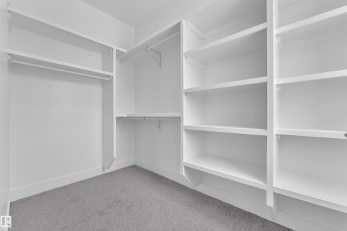 Well-appointed closet featuring white built-in shelving, hanging rods, and a carpeted floor - 110 Eldridge Point(E), St. Albert, AB - Indoor With Storage