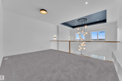 This space features plush gray carpeting, white walls, and a contemporary ceiling light fixture - 110 Eldridge Point(E), St. Albert, AB - Indoor Photo Showing Other Room