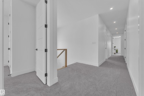 This property features a hallway with light gray carpet, white walls, and recessed lighting - 110 Eldridge Point(E), St. Albert, AB - Indoor Photo Showing Other Room