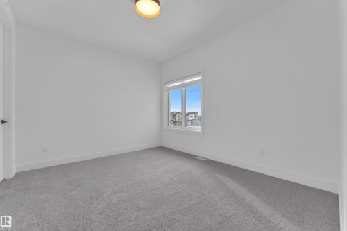 The room features light gray carpet, white walls, and a window with a view of other properties - 110 Eldridge Point(E), St. Albert, AB - Indoor Photo Showing Other Room