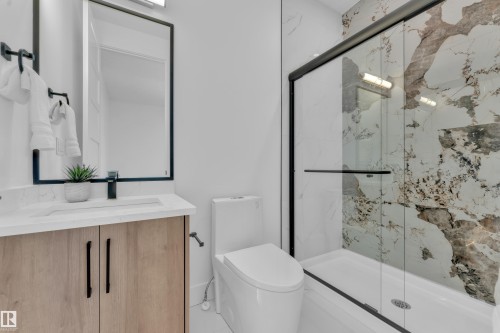 This bathroom features a contemporary vanity with light wood cabinetry, a white countertop, and a sleek black framed mirror - 110 Eldridge Point(E), St. Albert, AB - Indoor Photo Showing Bathroom