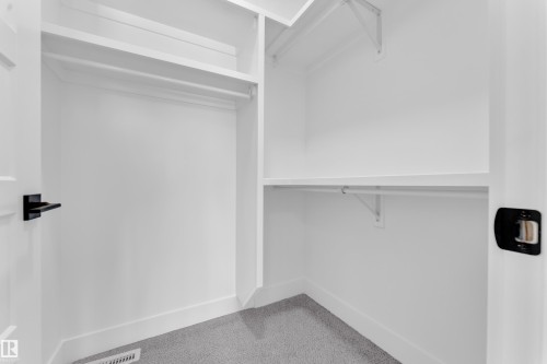 This spacious closet features carpeted flooring, white shelving, and hanging rods - 110 Eldridge Point(E), St. Albert, AB - Indoor With Storage
