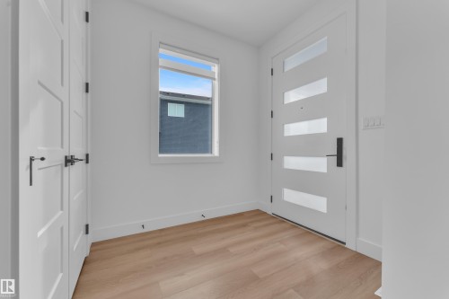 The entryway features light wood flooring, a white modern style front door with frosted glass panels, and a window providing natural light - 110 Eldridge Point(E), St. Albert, AB - Indoor Photo Showing Other Room