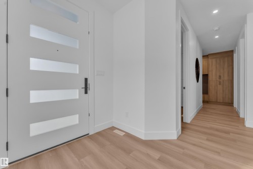 The property features a contemporary white entry door with frosted glass panels and sleek black hardware - 110 Eldridge Point(E), St. Albert, AB - Indoor Photo Showing Other Room