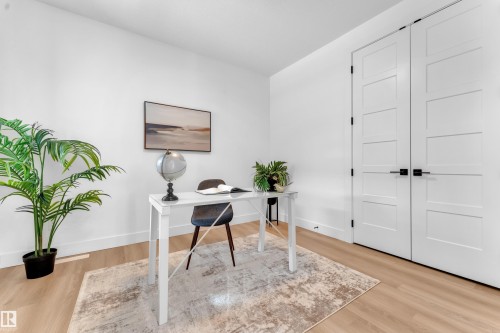 The room features light wood flooring, white walls, and a modern two-panel door design with black hardware - 110 Eldridge Point(E), St. Albert, AB - Indoor Photo Showing Office