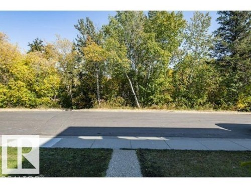 The property features a well-maintained lawn and a gravel pathway leading to a paved sidewalk - 14631 Summit Drive, Edmonton, AB - Outdoor