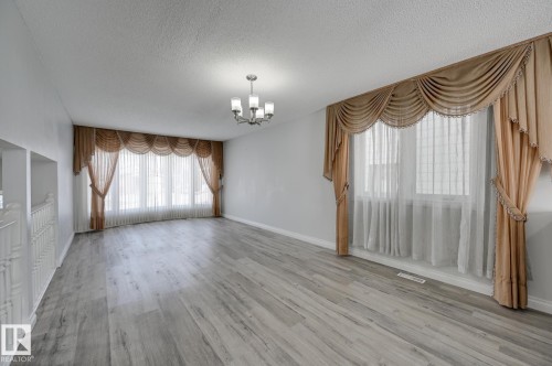 The property features light-toned flooring, white walls, and a multi-pane window with sheer curtains and draped valances - 8507 152B Avenue, Edmonton, AB - Indoor Photo Showing Other Room