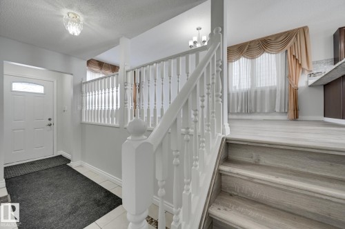 Entryway featuring a white door with an arched window, a white balustrade, and a staircase with light-toned steps - 8507 152B Avenue, Edmonton, AB - Indoor Photo Showing Other Room