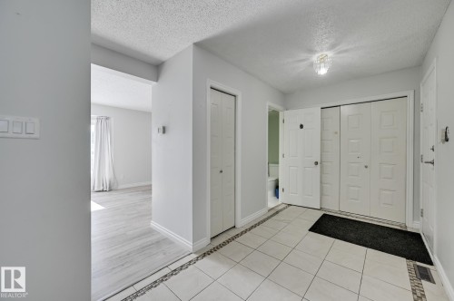 The entryway features light-colored tile flooring with a decorative border, a light fixture, and white bi-fold doors - 8507 152B Avenue, Edmonton, AB - Indoor Photo Showing Other Room
