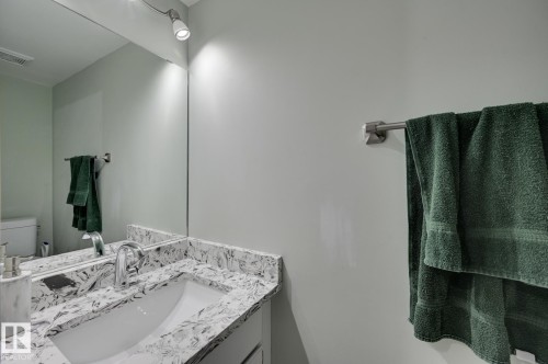 Bathroom vanity with a white rectangular sink, a polished chrome faucet, and a large mirror - 8507 152B Avenue, Edmonton, AB - Indoor Photo Showing Bathroom