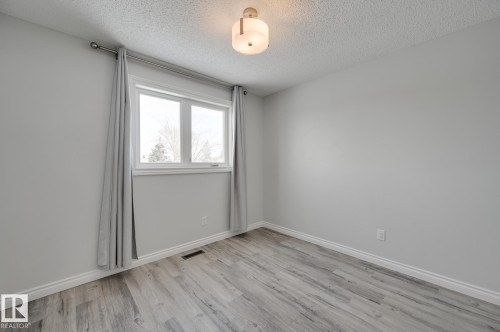 This room features light grey walls and light-toned, wide plank flooring - 8507 152B Avenue, Edmonton, AB - Indoor Photo Showing Other Room