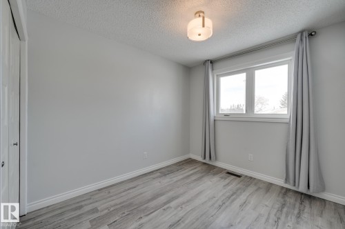 This room features a window providing natural light, light-toned walls, and wood-style flooring - 8507 152B Avenue, Edmonton, AB - Indoor Photo Showing Other Room