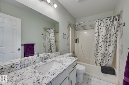 Bathroom featuring a white vanity with a patterned countertop, an integrated sink, and a large mirror - 8507 152B Avenue, Edmonton, AB - Indoor Photo Showing Bathroom