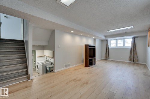 Spacious room featuring light-toned hardwood flooring, recessed lighting, and a window with curtains - 8507 152B Avenue, Edmonton, AB - Indoor Photo Showing Other Room