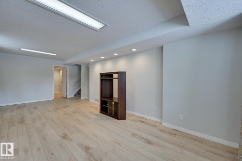 Spacious room featuring light-colored hardwood flooring, light grey walls, and a variety of ceiling lighting including recessed lights and fluorescent fixtures - 8507 152B Avenue, Edmonton, AB - Indoor Photo Showing Other Room