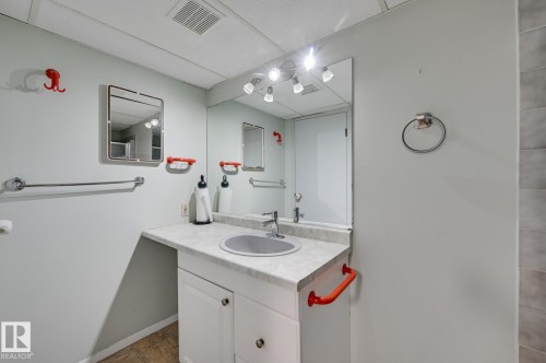 Bathroom featuring a vanity with a countertop, an integrated sink, and a large mirror with overhead lighting - 8507 152B Avenue, Edmonton, AB - Indoor Photo Showing Bathroom